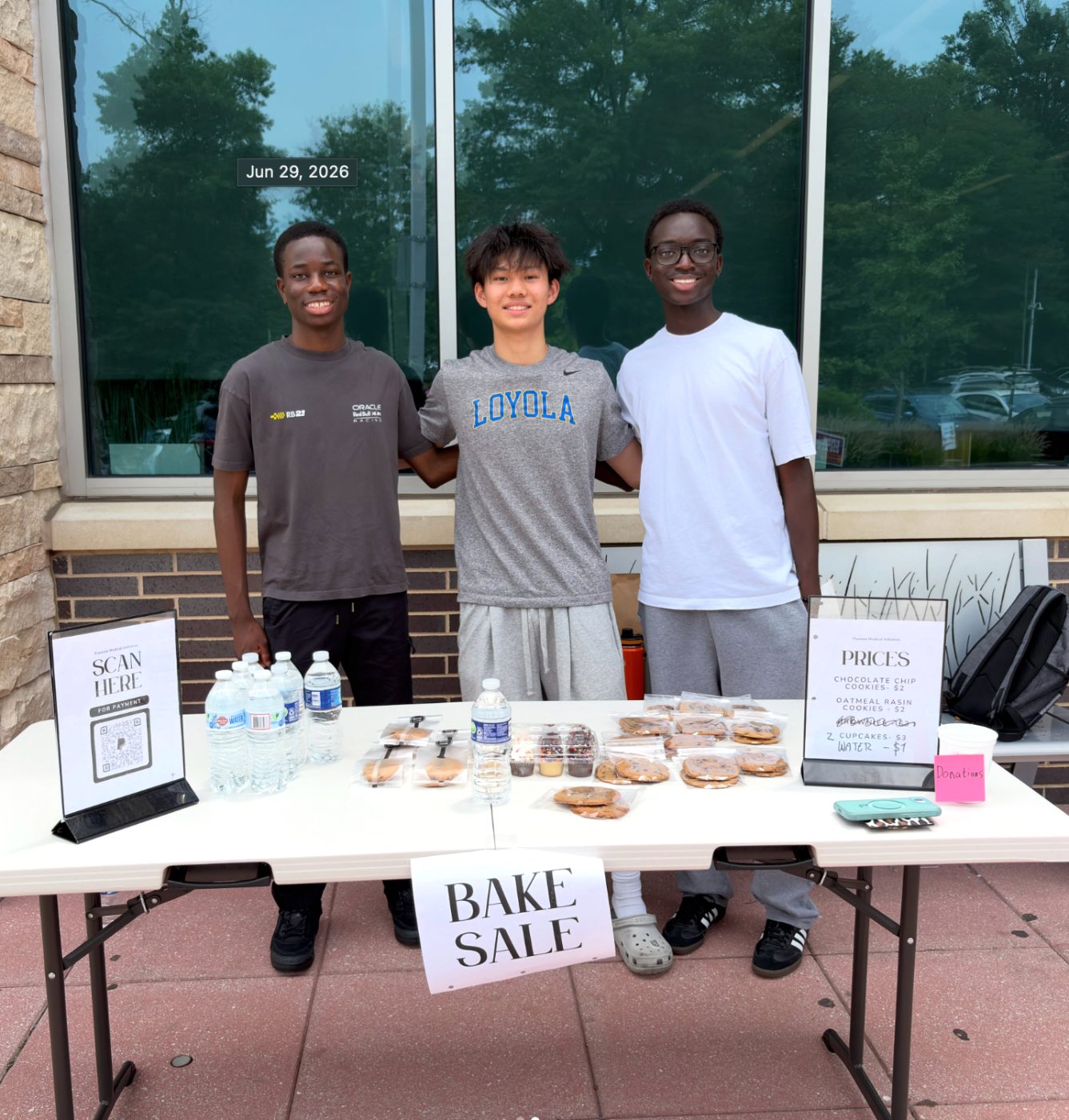 Baltimore branch members at their bake sale table with baked goods and a prices sign