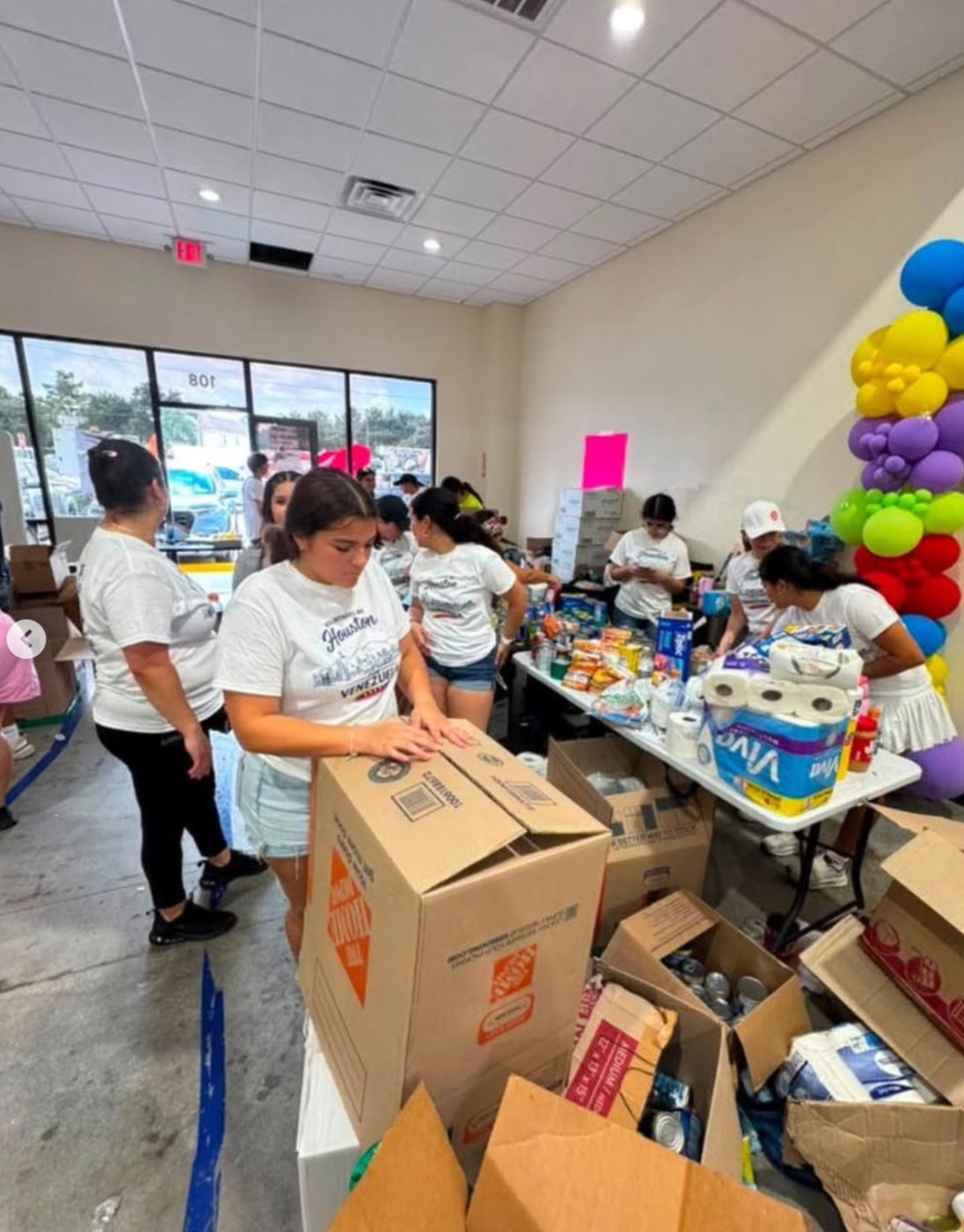 Volunteers in matching shirts sorting boxes of donated medical and household supplies